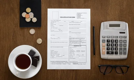 Visa application form, passport, coins and coffee on wooden background, flat lay, visa processing, immigration.